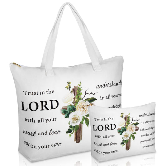 A studio product photograph featuring a white tote bag and a matching smaller zippered pouch, both printed with a floral cross design and the Bible verse Proverbs 3:5-6, "Trust in the LORD with all your heart and lean not on your own understanding
