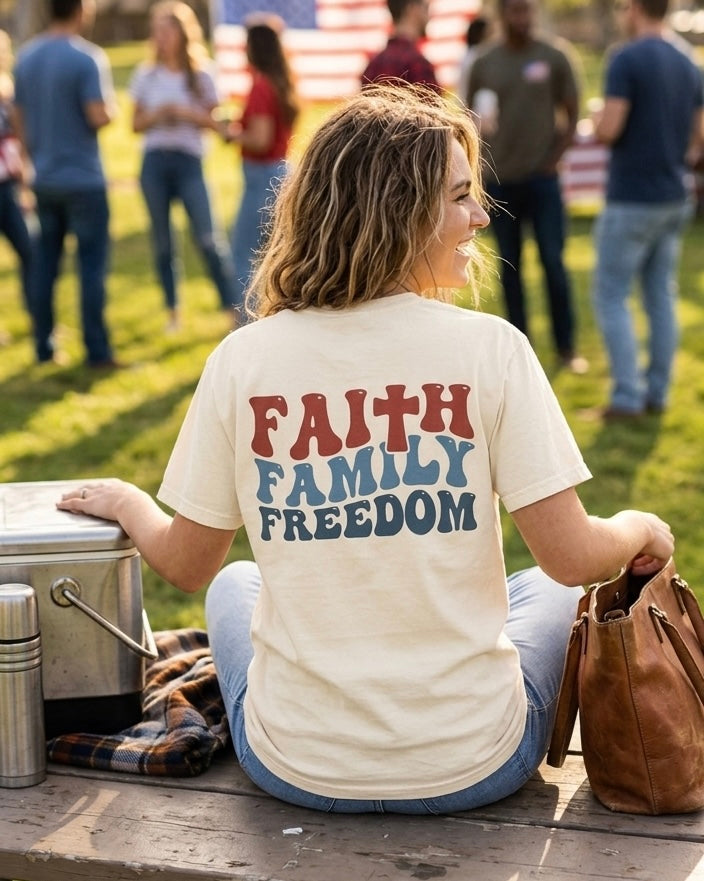 Back view of a woman wearing a vintage-style Faith, Family, Freedom graphic tee at a patriotic family event.