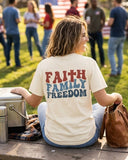 Back view of a woman wearing a vintage-style Faith, Family, Freedom graphic tee at a patriotic family event.