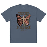 A blue oversized t-shirt featuring a Christian graphic design of a butterfly, a wooden cross, and flowers with the text Created With A Purpose and the Bible verse reference Ephesians 2:10.-indigo.