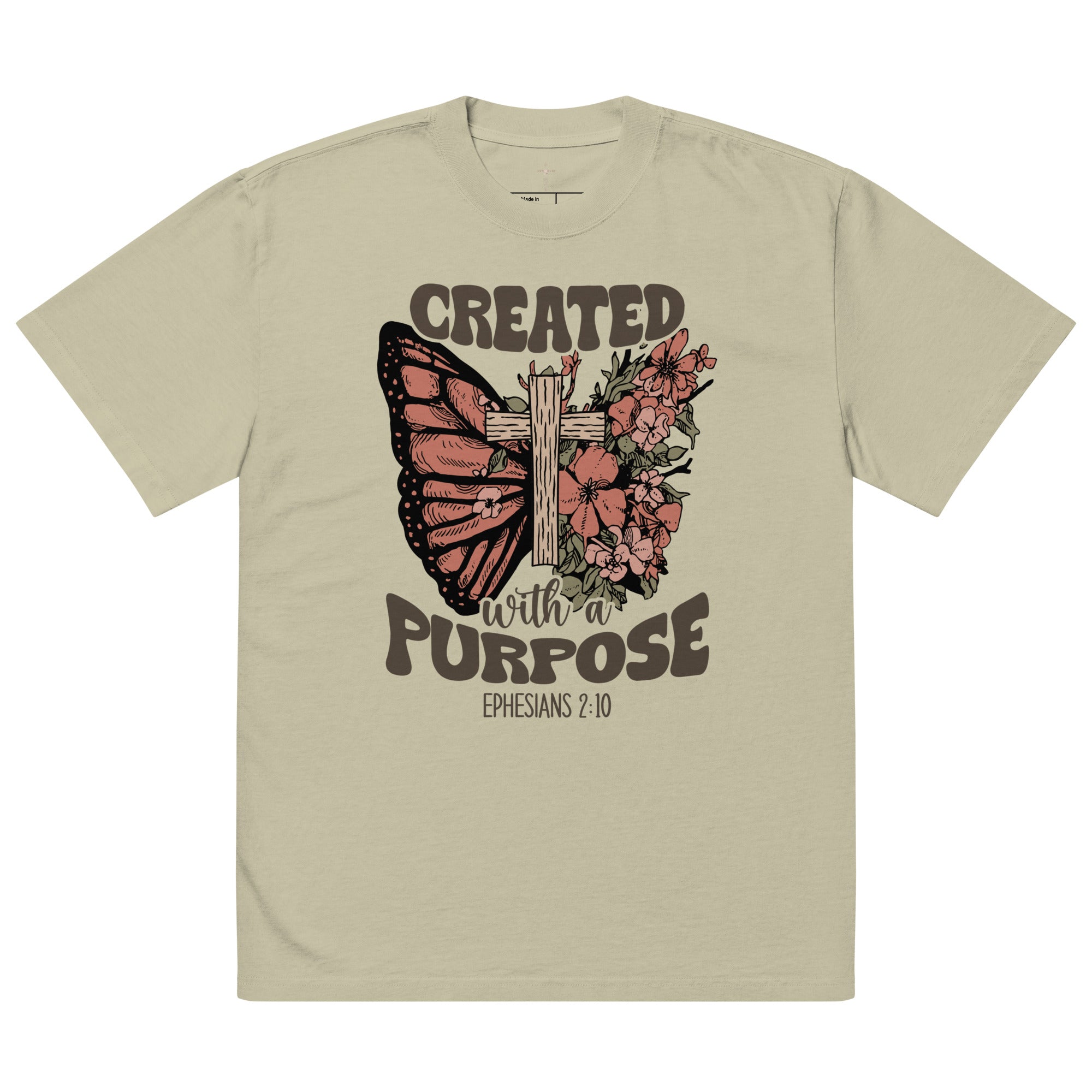 An isolated product view of a tan, faded, boho-style Christian t-shirt featuring a floral cross, butterfly, and the bible verse Ephesians 2:10