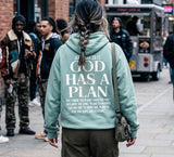 Back view of a person wearing a sage green Christian hoodie featuring the inspirational "God Has A Plan" scripture design, ideal for intentional and modest streetwear