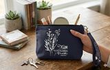 A deep navy blue canvas Christian cosmetic bag featuring white floral line art and the inspirational text "Faith does not make things easy, it makes them possible Luke 1:37 and Luke 18:1" with a navy wrist strap.