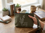 An olive green canvas Christian cosmetic pouch featuring white wildflowers and the motivational scripture "Always pray and never give up Luke 18:1" with a matching green wrist strap.