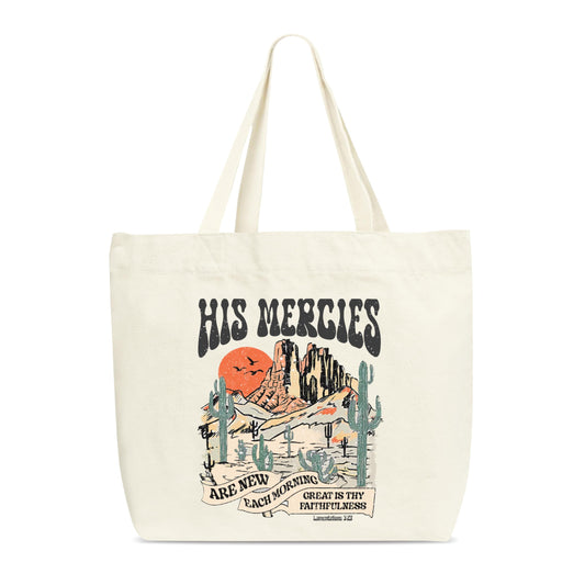 A studio product shot of a cream-colored canvas tote bag centered on a plain white background, displaying a graphic design of a desert scene with the Bible verse reference "Lamentations 3:23" at the bottom