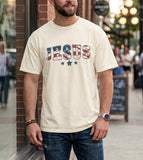 trendy man wearing an ivory patriotic "JESUS" graphic t-shirt and blue jeans, styled for urban Christian street wear.
