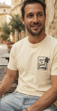 Man wearing a cream-colored faith apparel graphic t-shirt with a "God is Good" stamp design, styled for urban Christian streetwear.