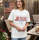 A lifestyle photo of a woman in an America Needs Jesus t-shirt standing in front of an American flag, casual faith-based fashion.