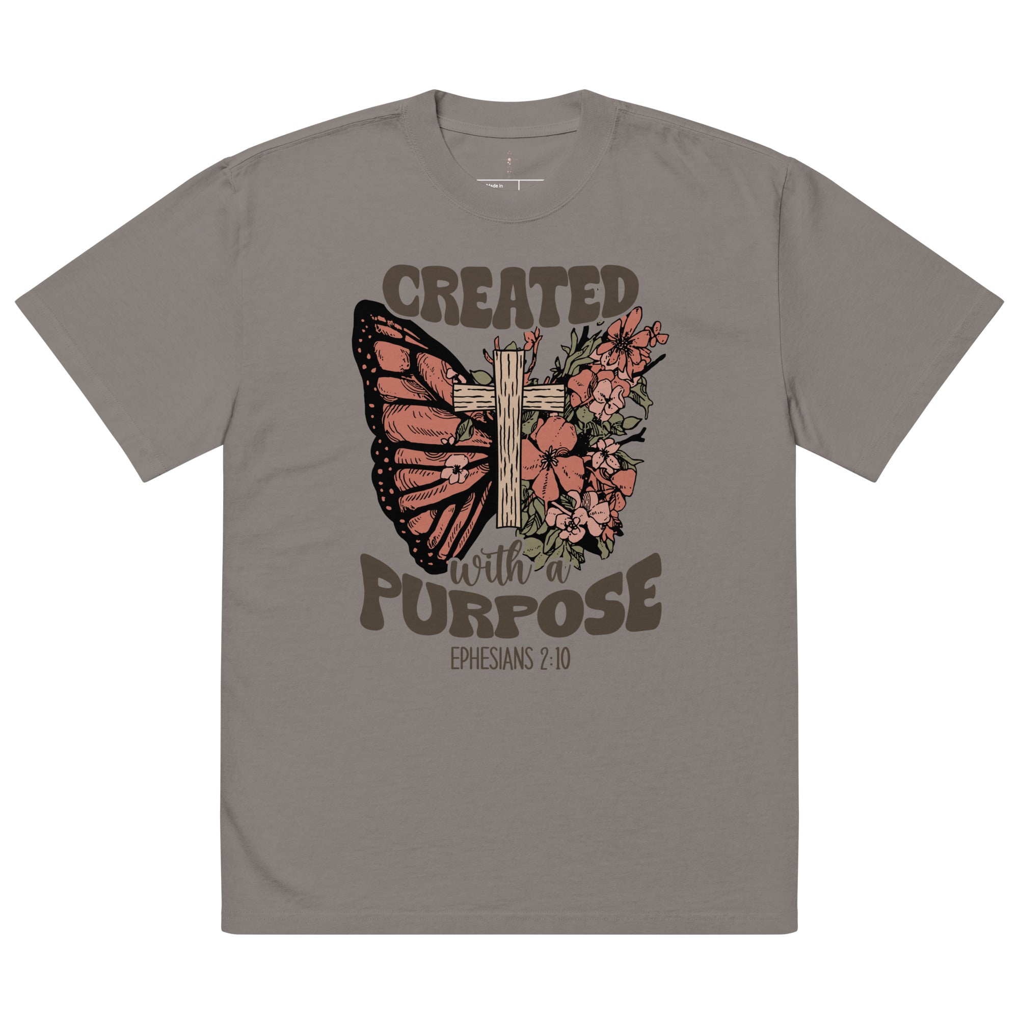 An isolated product view of a grey-brown vintage-style Christian t-shirt with a graphic of a butterfly, cross, and the scripture Created With A Purpose.