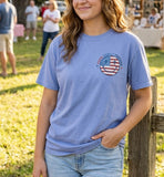 Woman wearing a blue t-shirt with an American flag graphic in a casual outdoor setting. Christian t-shirt. 